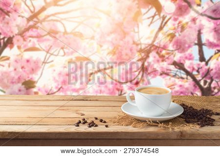 Coffee Cup With Coffee Beans On Wooden Table Over Blossom Cherry Tree Blurred Background With Copy S