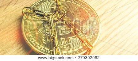 Closeup Of Golden Bitcoin In Golden Chains Laying On Wooden Background