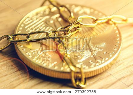 Closeup Of Golden Coin In Golden Chains Laying On Wooden Background