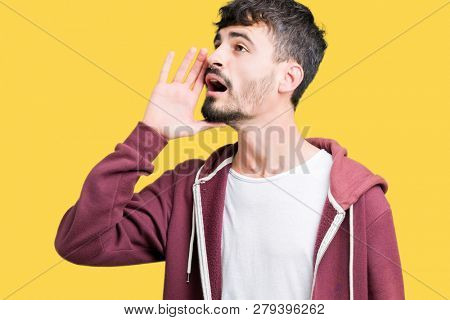 Young handsome man over isolated background shouting and screaming loud to side with hand on mouth. Communication concept.