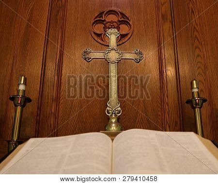 Very Old Gold Cross With Crown Of Thorns And Open Blurred Bible On Wooden Altar