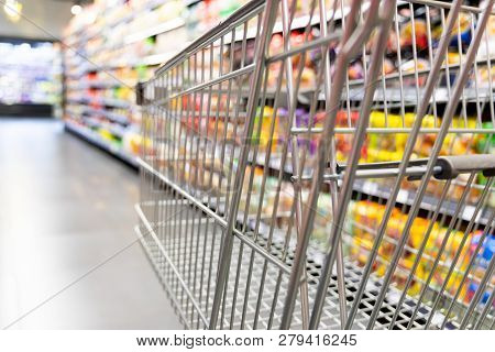 Shopping Trolley Cart Against Supermarket Aisle Blurred Background