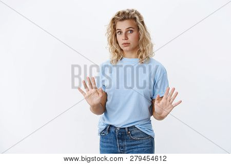 No Thanks. Alarmed And Intense Young Attractive Woman With Short Curly Hair Holding Palms Near Chest