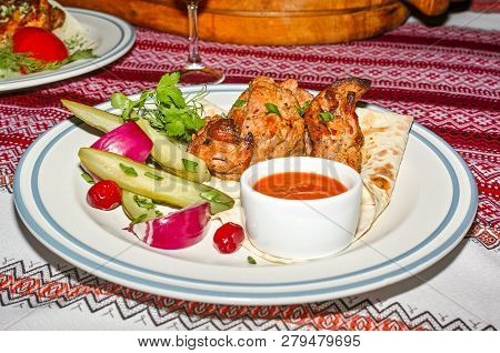 Slices Of Kebab Meat On Pita Bread With Pickled Cucumber, Onions And Greens. Served On A Plate With 