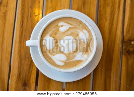 Cup Of Coffee With Heart Pattern In A White Cup On Wood Table