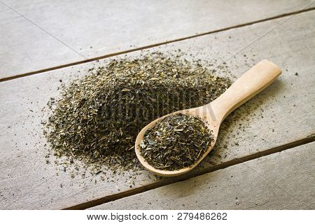 Spoon Of Dried Green Tea Leaves On Wooden Background