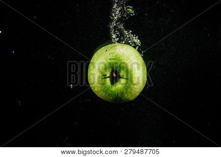 Green Apple Splashes Water Falling On Black Background