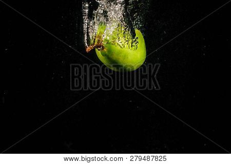 Green Pear Falls In Water On Black Background
