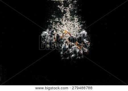 Large Bunch Of Black Grape Falls On Black Background