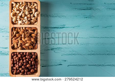 Compartmental Dish With Nuts On Blue Wooden Table. Cashew, Hazelnut, Almond.