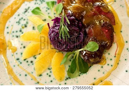 Nice Looking Diverse Dish. Nice Looking Dish With Meat, Orange Sauce, Lemons Slices, Rosemary And Be