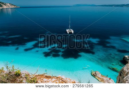 White Catamaran Yacht At Anchor In Calm Clear Azure Water Lagoon. Unrecognizable Tourists Relax And 