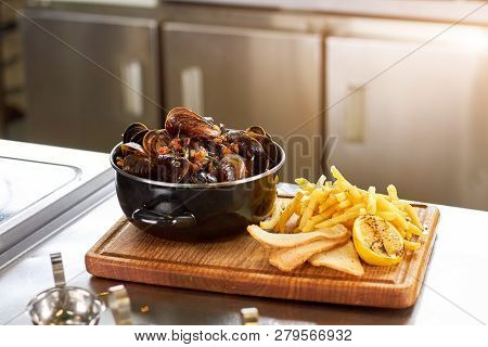 Dish With Mussels And French Fries. Delicatessen Dish - Sausepan Of Mussels, Fries, Bread And Lemon.