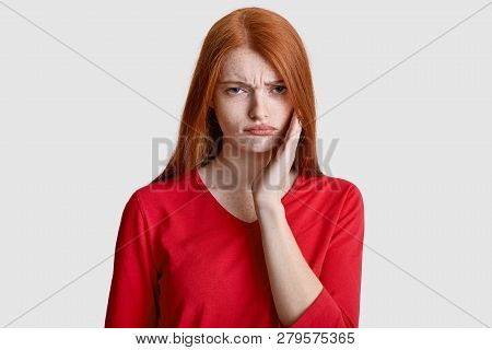 Displeased Red Haired Woman With Freckled Skin, Keeps Hand On Cheek, Suffers From Toothache, Has Sen