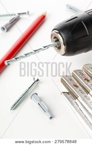 Wall Plug Dowel With Screw, Electric Power Drill, Folding Rule And Pencil On White Table - Home Impr