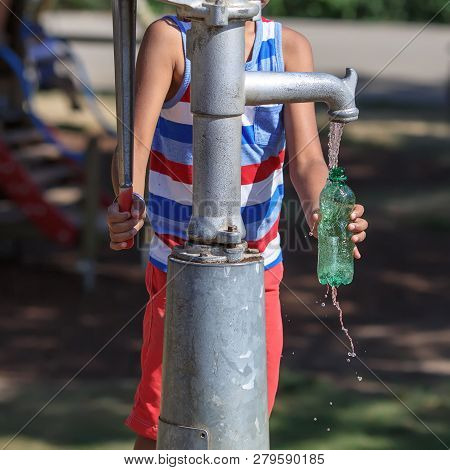 A Young Boy Collects Clean Water From A Street Standpipe In The Park. Vienna, Austria, Europe.