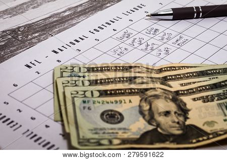 Football Office Pool Grid For Sports Betting Concept With Money And A Pen, Partially Completed Boxes