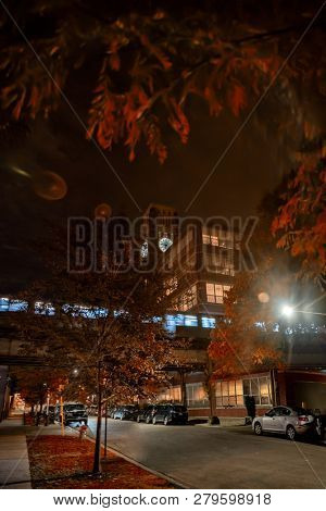 Night street cityscape with an elevated subway train station and a vintage clock tower in Chicago