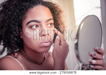 Attentive Dark-skinned Woman Checking Effect Of Eye Patches