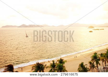 Sunset, mountains, ocean waves and beach, Acapulco de Juarez, Mexico, the Pacific Ocean, North America. Photo toned in orange color