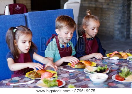 Kids In A Cafe Learning How To Cook Burgers