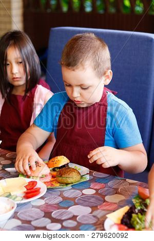 Kids In A Cafe Learning How To Cook Burgers