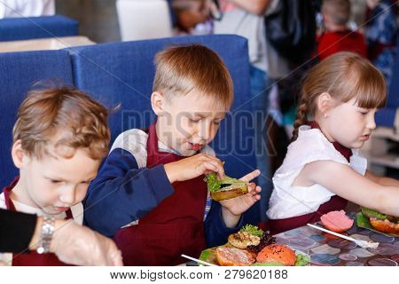 Kids In A Cafe Learning How To Cook Burgers