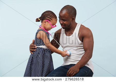 Happy Father And Daughter Playing Doctor With A Toy Stethoscope Against Pale Blue Background. She We