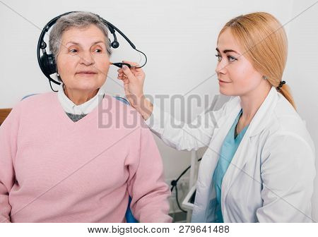 Audiologist Doing Hearing Exam With Special Headphones To A Aged Patient
