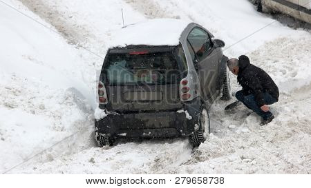 Man Digging Up Up Stuck In Snow Car. Car Wheel Stuck In The Snow. Driving In Adverse Weather Conditi