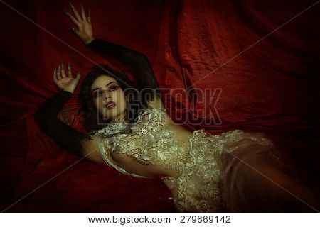 vampire, demonic woman dressed in white lace and silver jewelry. has fangs and thick brown hair