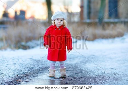 Outdoor Winter Portrait Of Little Cute Toddler Girl In Red Coat And White Fashion Hat Barret. Health