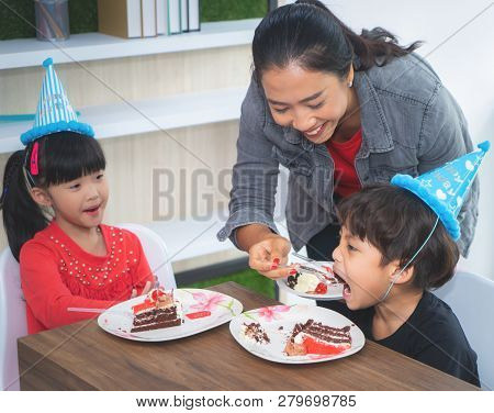 Mother Is Feeing Her Children Birthday Cake In A Brithday Party