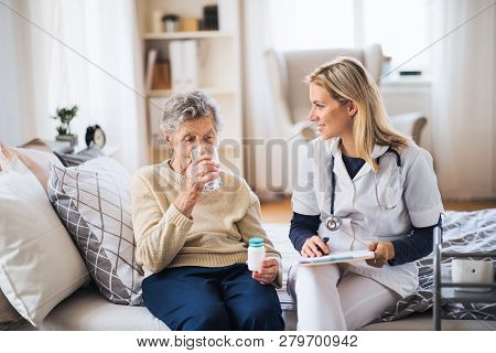 A Health Visitor And A Senior Woman At Home, Taking Pills.