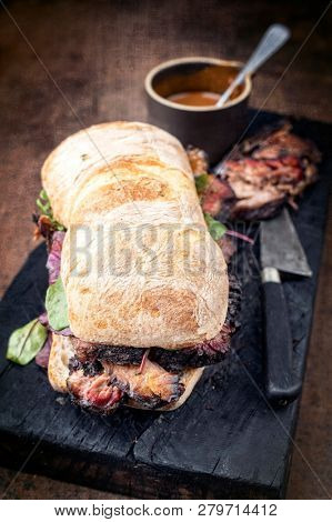Traditional barbecue pulled pork piece of Bosten butt as sandwich with lettuce as closeup on a black board 