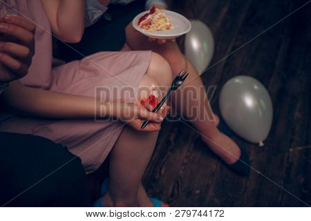 Detailed View On A Girls Knees With A Piece Of Cake Falling Down. Womans Hand With Silver Fork Is Tr