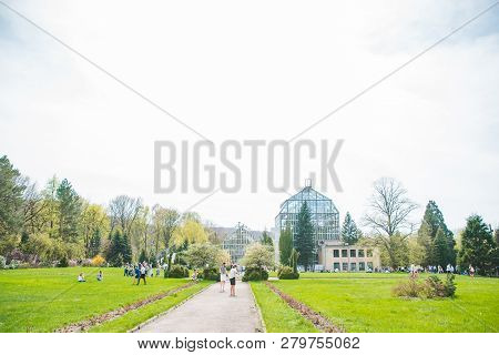 Lviv, Ukraine - April 15, 2018: People Walking By Botanic Garden Looking Blooming Flowers. Spring Is