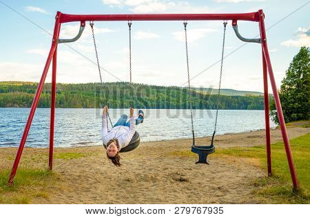 Young Woman On Swing In Oppstrynsvatn Lake In The Municipality Of Stryn In Sogn Og Fjordane County I