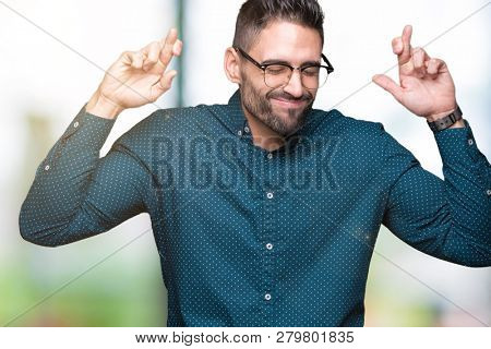 Young handsome business man wearing glasses over isolated background smiling crossing fingers with hope and eyes closed. Luck and superstitious concept.