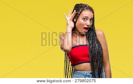 Young braided hair african american with pigmentation blemish birth mark over isolated background smiling with hand over ear listening an hearing to rumor or gossip. Deafness concept.