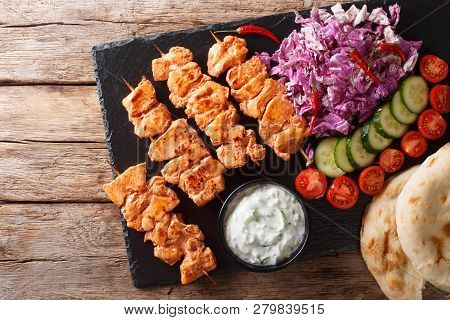 Close-up Of Chicken Skewers With Fresh Salad, Yogurt Sauce And Pita Bread On A Slate. Horizontal Top