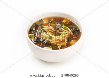 A Photo Of A Bowl Of Miso Soup With Tofu, Scallions, Noodles, And Wakame Algae, On A White Backgroun