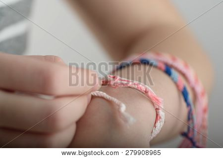 Horizontal Toned Shot Of A Female Hand Wearing Braided Bracelets.