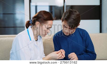 Woman Shows A Young Man A Hearing Aid.