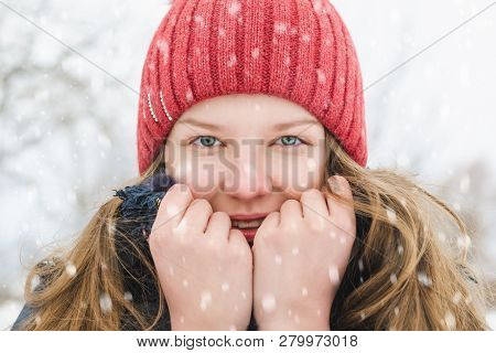 A Young Blonde Girl In A Coral-colored Hat Is Holding A Collar In Her Hands To Make It Warmer, And I