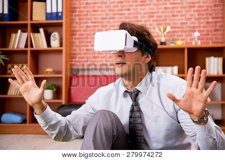 Young employee with virtual glasses during break in the office 