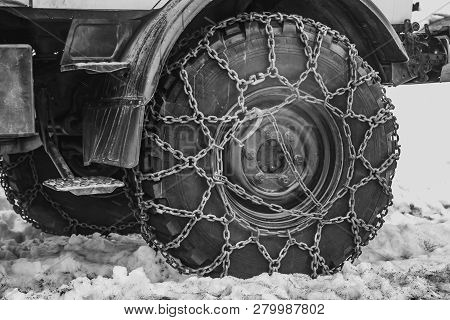 Snow Chains At The Front Wheel Of A Grader At The Highway In Winter