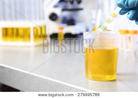 Laboratory Assistant Putting Litmus Paper Into Urine Sample On Table, Closeup With Space For Text. M