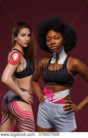 Kinesiology Taping. Two Young Female Athletes On Red Background With Kinesiology Tape On Neck, Shoul