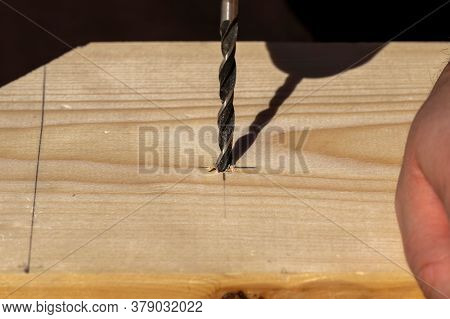 A Closeup Portrait Of A Person Drilling A Hole In A Wooden Plank On The Drawn Pencil Marking. The Wo
